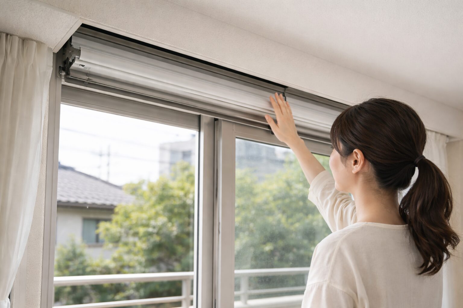日本人女性が天井納まりのシャッターを点検